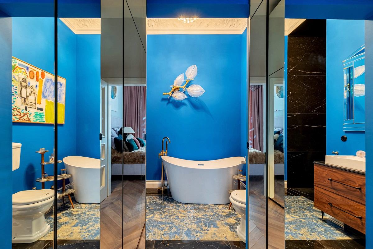 Zdjęcie przedstawia wnętrze łazienki z małą wanną, kamienną podłogą oraz bogatą sztukaterią przysufitową.