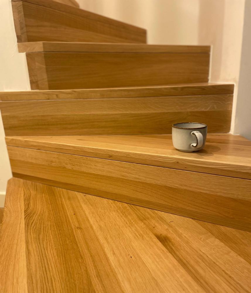 Zdjęcie pokazuje nowo złożone schody drewniane. Ich forma jest nowoczesna, prosta i pasuje do wnętrza.