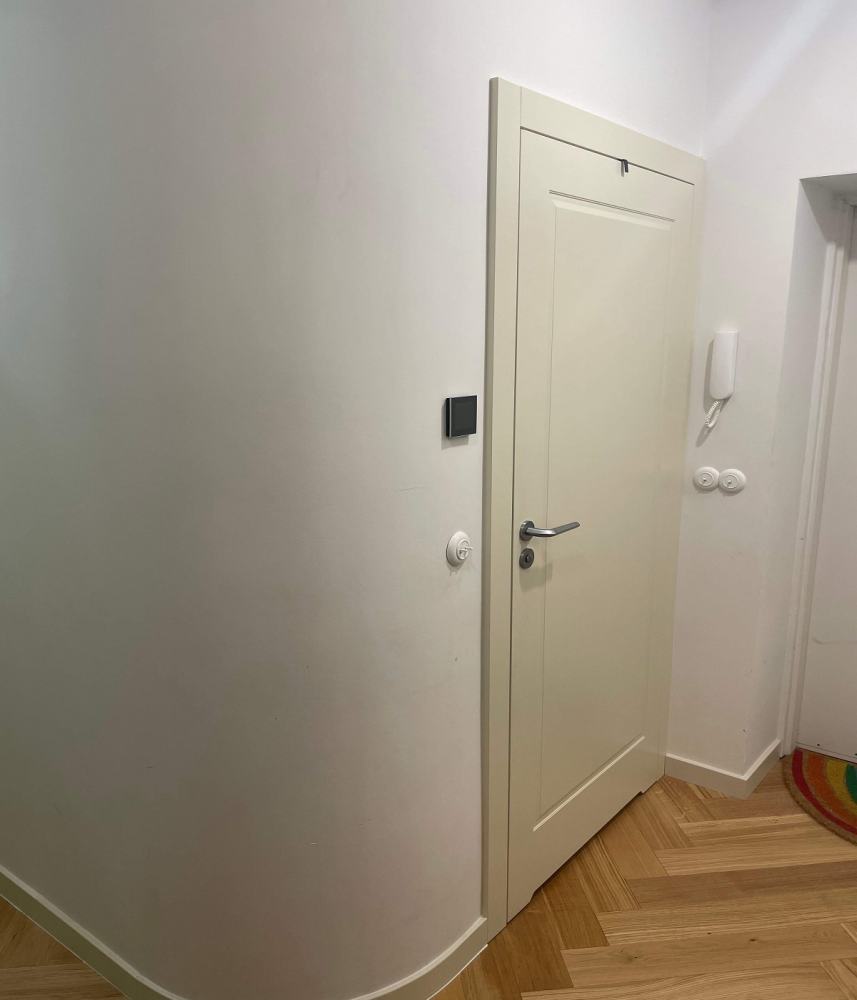 Na zdjęciu widoczny jest fragment pomieszczenia, z uwagą skierowaną na białe, eleganckie drzwi wejściowe.