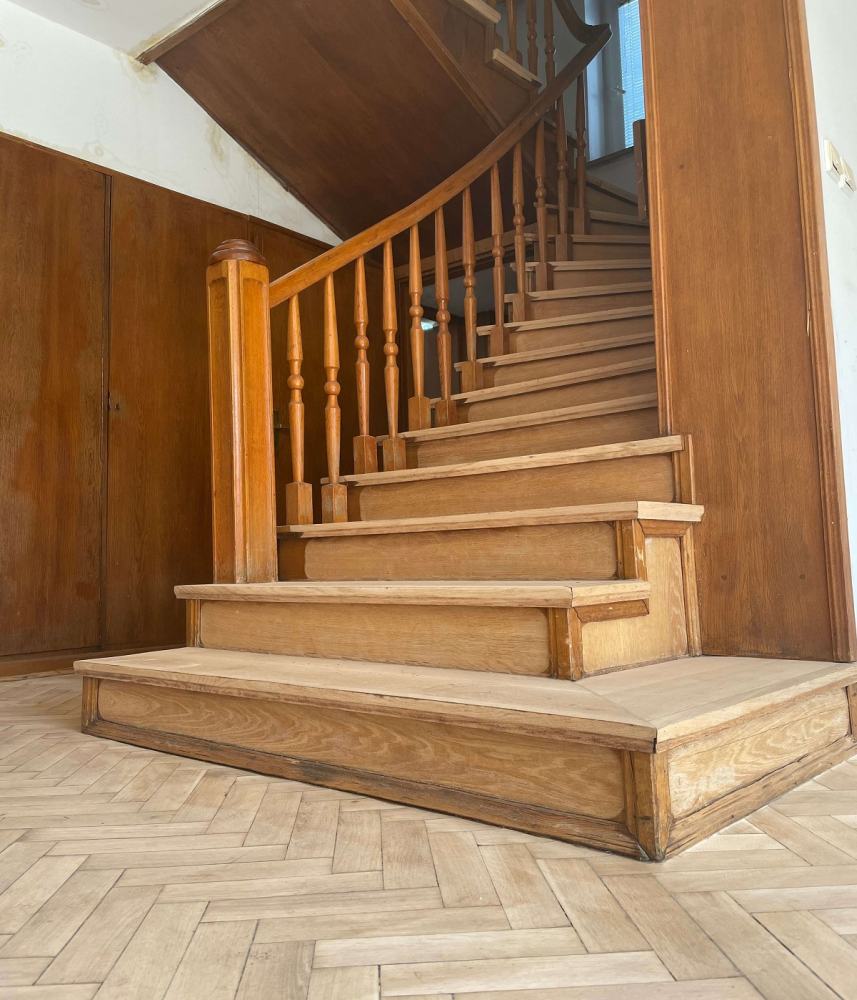 Zdjęcie pokazuje drewniane schody w domu jednorodzinnym przygotowane do prac renowacyjnych.