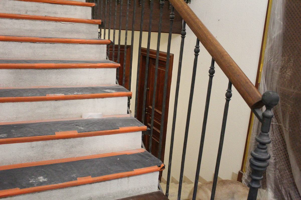Zdjęcie przedstawia schody w domu jednorodzinnym zabezpieczone podczas prac nad renowacją podłogi.