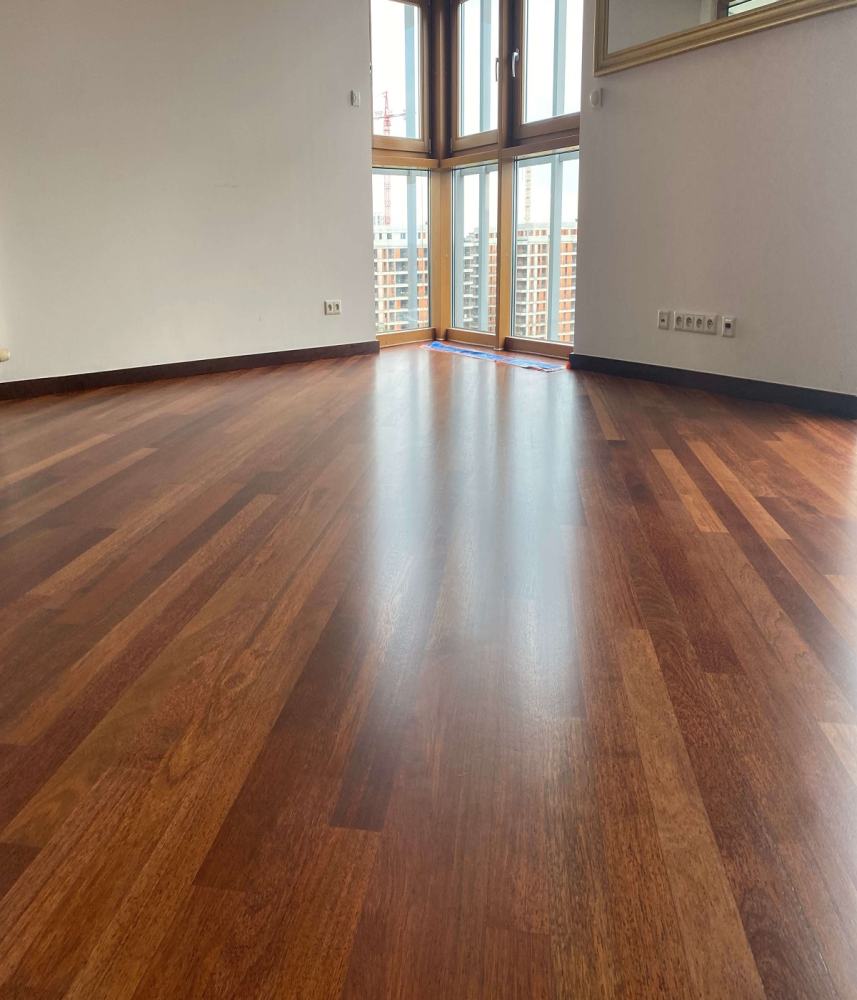 Na zdjęciu widoczne pomieszczenie, które zdobi wycyklinowana i polakierowana podłoga z drewna merabu, ułożonego we wzór pokładowy.