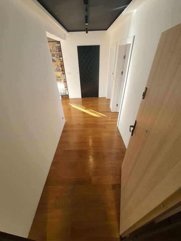 Na zdjęciu widoczny fragment korytarza w mieszkaniu. Uwagę przykuwa drewniana, dębową podłoga ułożona we wzór angielski, która została zakonserwowana twardym woskiem.