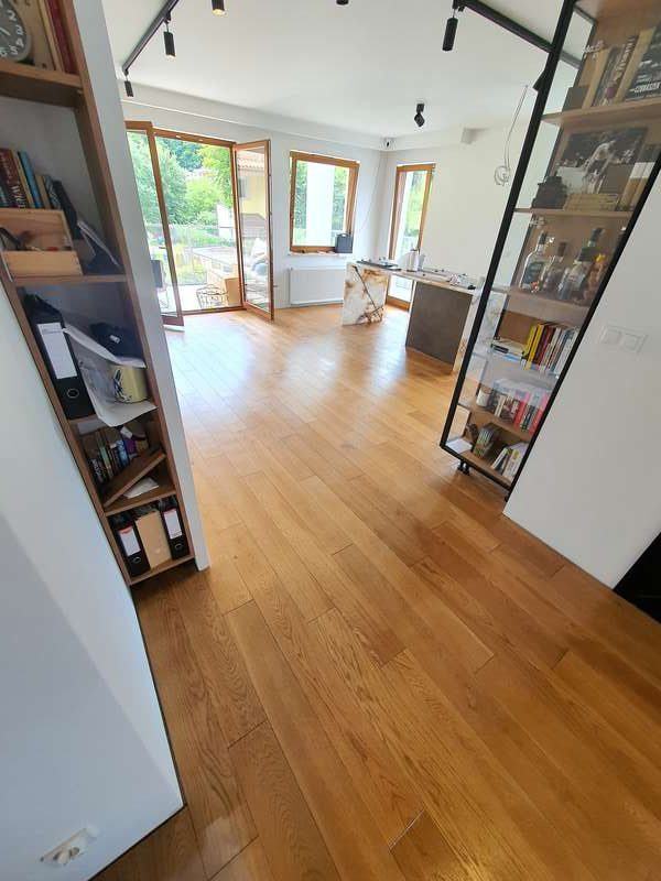 Zdjęcie prezentuje pomieszczenie, którego posadzka wykończona jest drewnianą, dębową podłogą ułożona we wzór angielski, która pięknie lśni po konserwacji twardym woskiem.