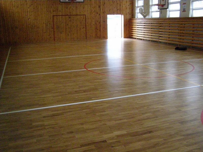 Na zdjęciu widzimy wnętrze sali gimnastycznej, która ma nowy parkiet drewniany z namalowanymi liniami boisk oraz lakierem zabezpieczającym.