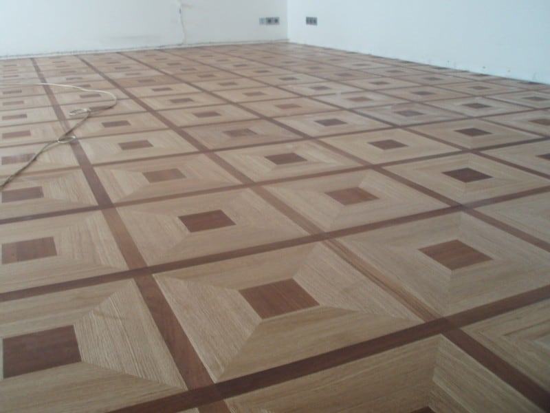 Zdjęcie pokazuje fragment podłogi pałacowej o ciekawym wzorze przypominającym kafle, który ułożony jest z różnokolorowych klepek drewnianych.