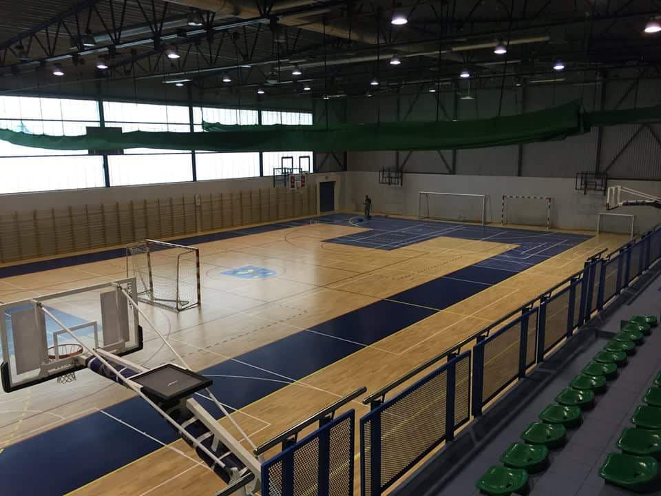 Zdjęcie przedstawia halę sportową po ułożeniu parkietu drewnianego, na którym wyznaczono odpowiednimi kolorami linie i strefy boisk.