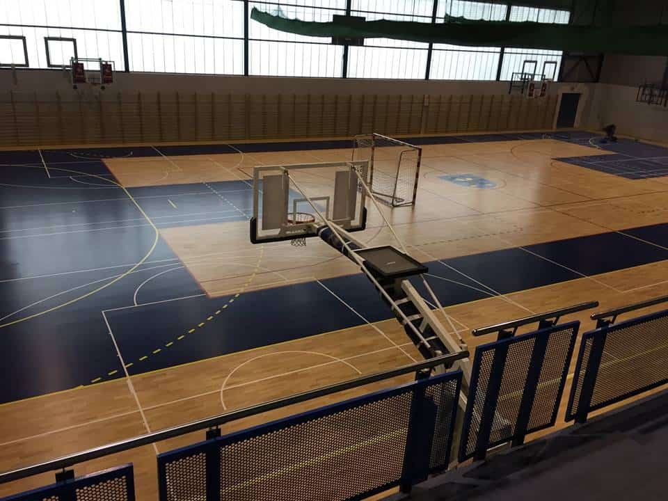 Zdjęcie wykonane z góry prezentuje podłogę hali sportowej, na której precyzyjnie wyznaczono i namalowano linie oraz strefy boisk.